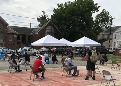 people sit at spaced-apart chairs outside