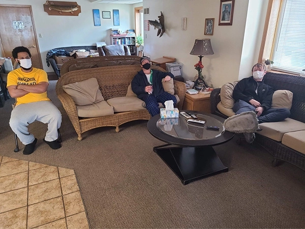 residents in surgical masks sit in a living room