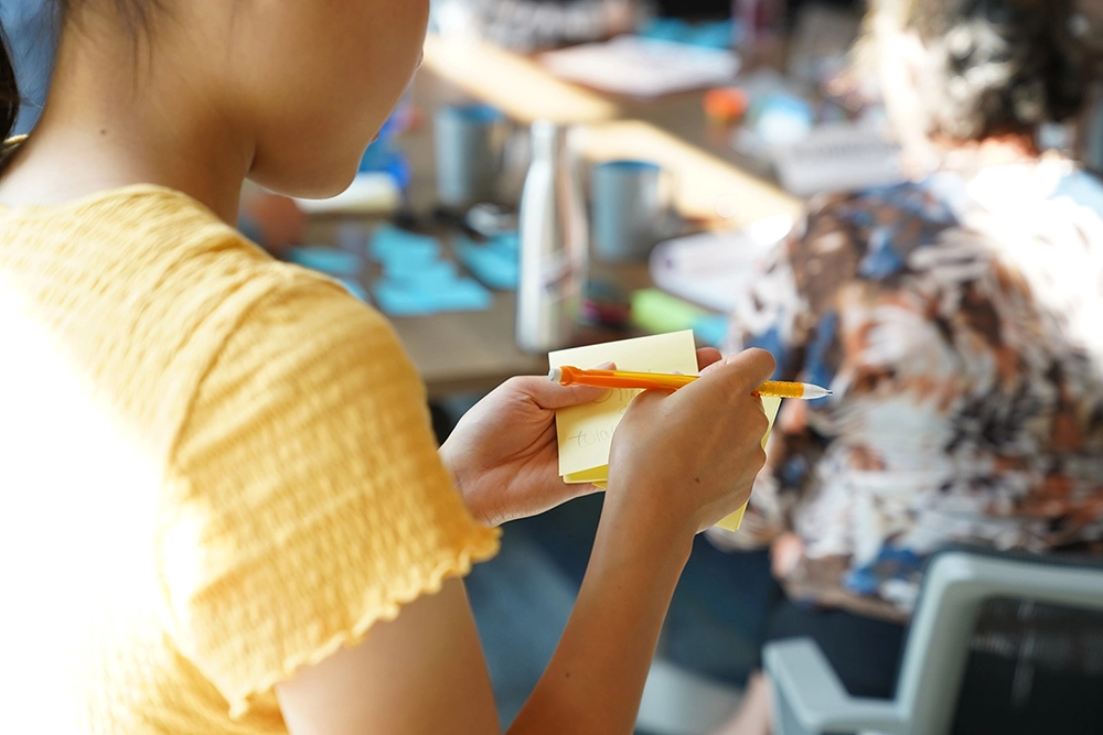 child holding post-it note pad and mechanical pencil