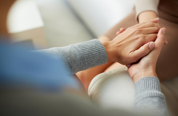 woman compassionately holding hand of another woman