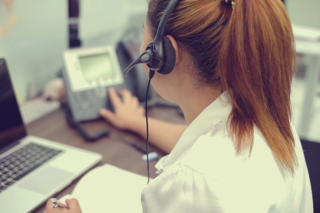 Woman in a headset reaching for a phone