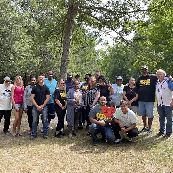 smiling group of people from the Connecticut Community for Addiction Recovery standing outside under a tree