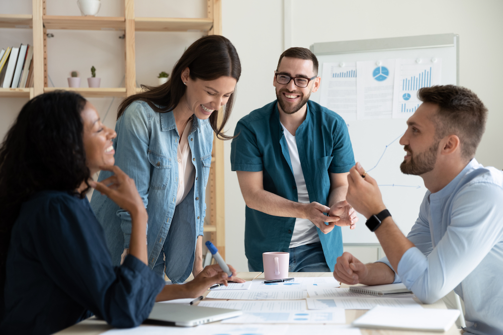 four smiling people gathered around a conference table