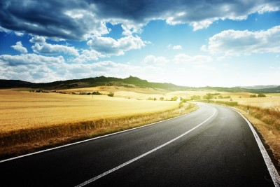 two-lane highway curving through golden fields