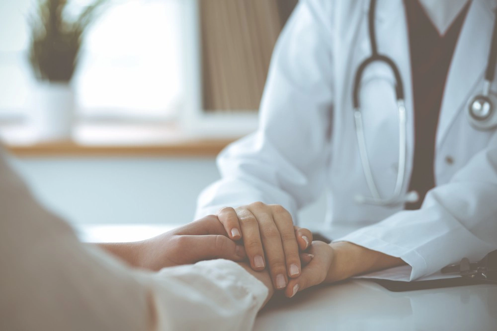 doctor holding patient's hand comfortingly