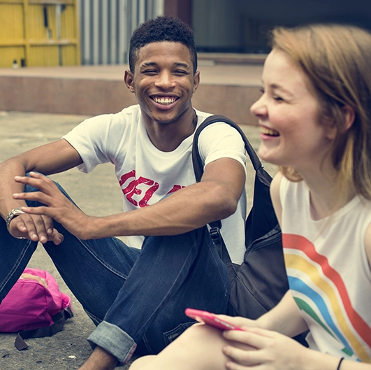 two youth sit together laughing