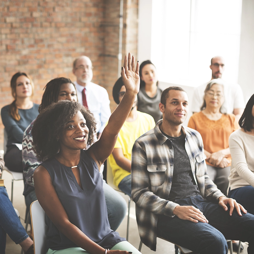 smiling Black woman raises her hand in small audience