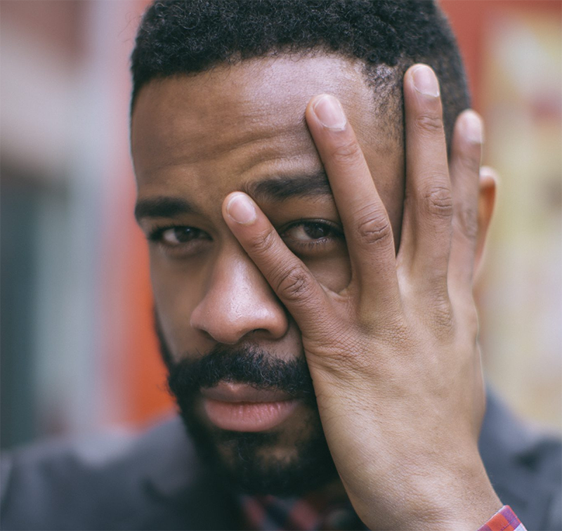 close-up of man looking at the camera and holding his hand in front of his face