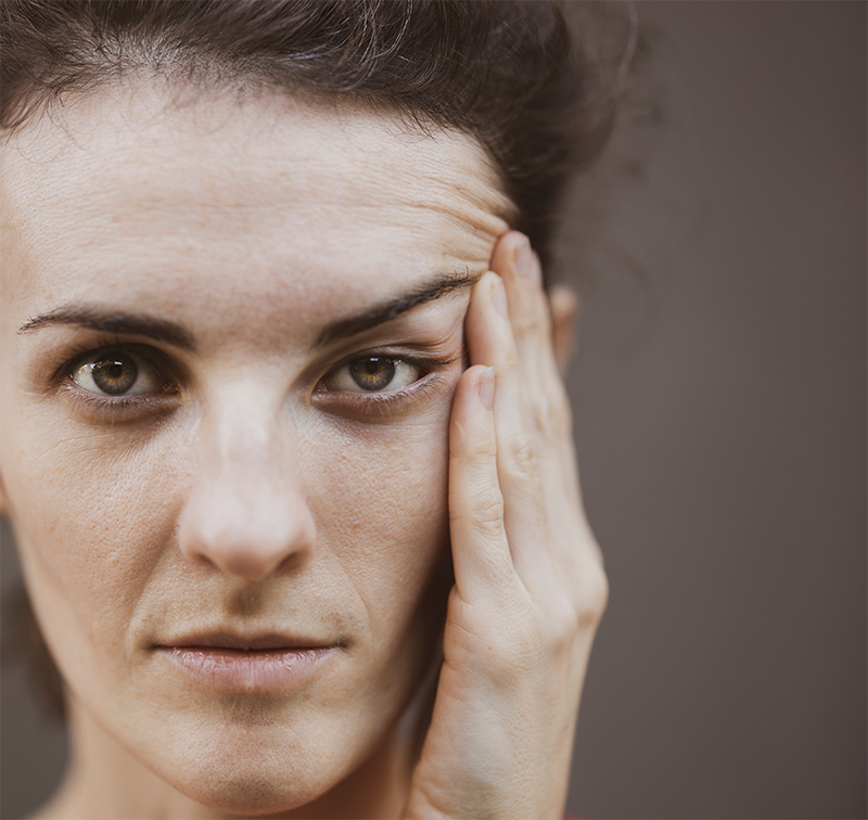 close-up of woman looking at the camera and holding the side of her head