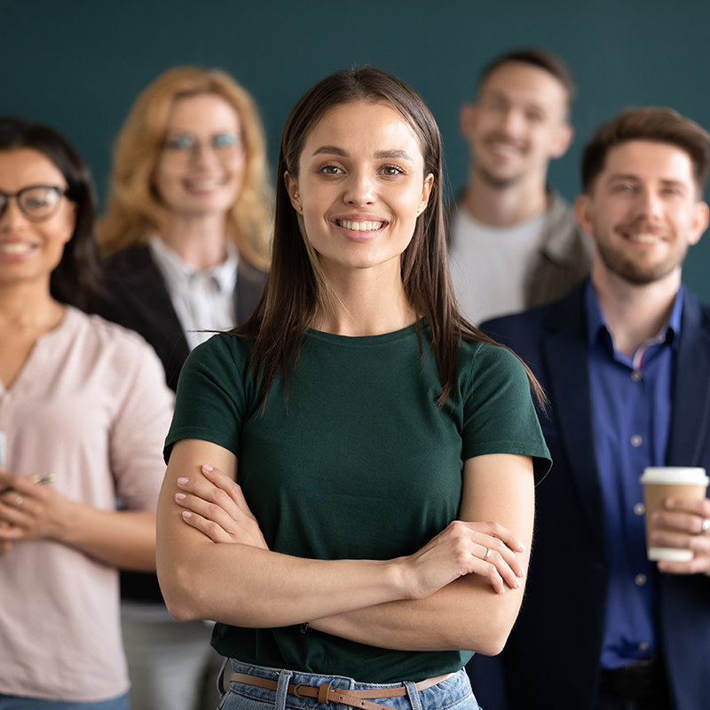 smiling young woman with her arms crossed stands in front of a group