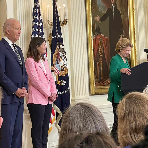 Senator Stabenow speaks in the East Room of the White House while President Biden looks on