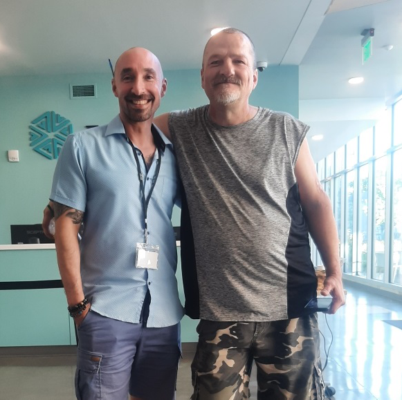 two men in recovery stand arm in arm