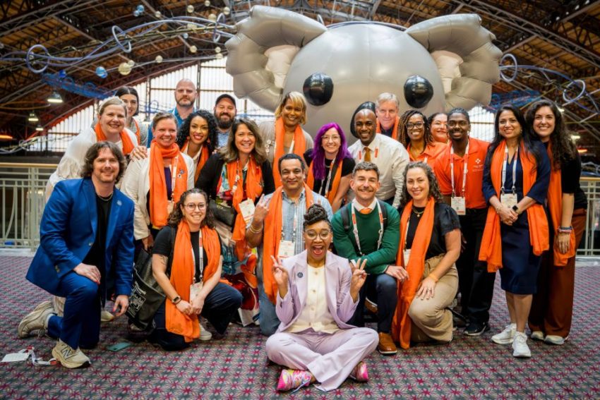 mhfa summit attendees pose for a group photo in front of an inflatable algee