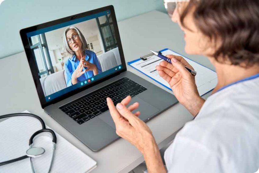 a woman speaks to someone on a video call on a laptop