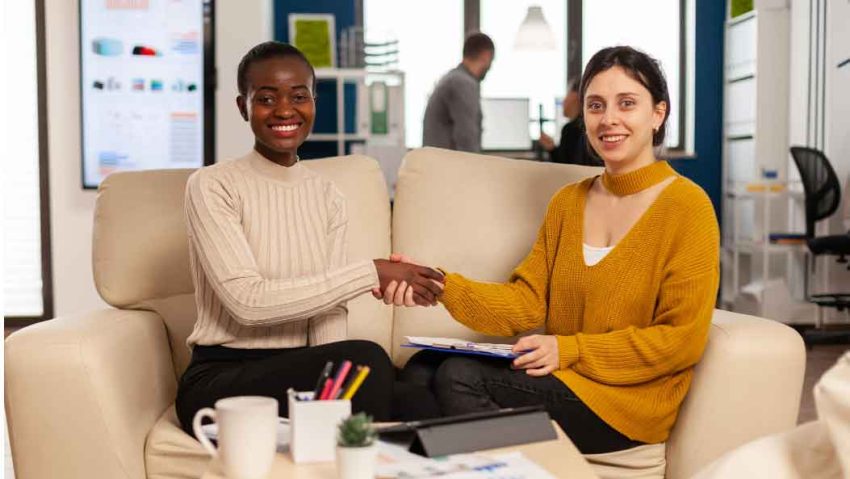 two people sitting on a couch shaking hands