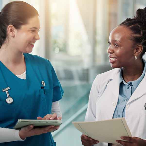 two women in medical clothes talk and smile