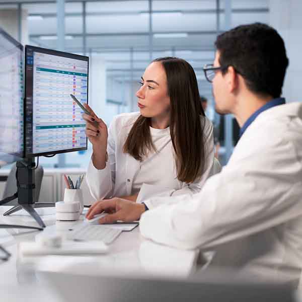 a woman points to something on a screen while a man looks on
