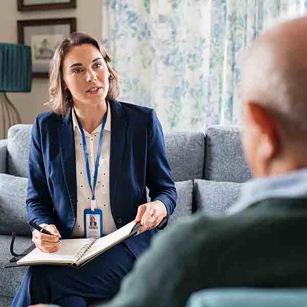 a woman speaks to an older man and fills out paperwork