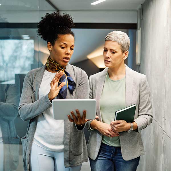 two women look at an ipad and discuss in an office